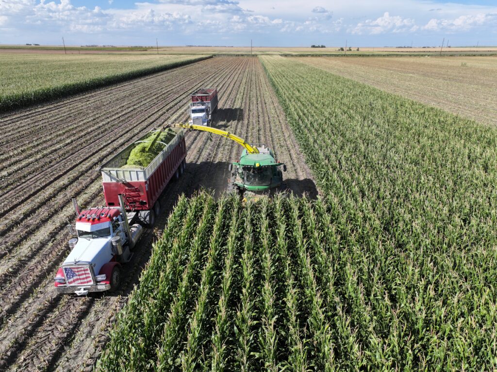 A truck and tractor in the middle of an open field.