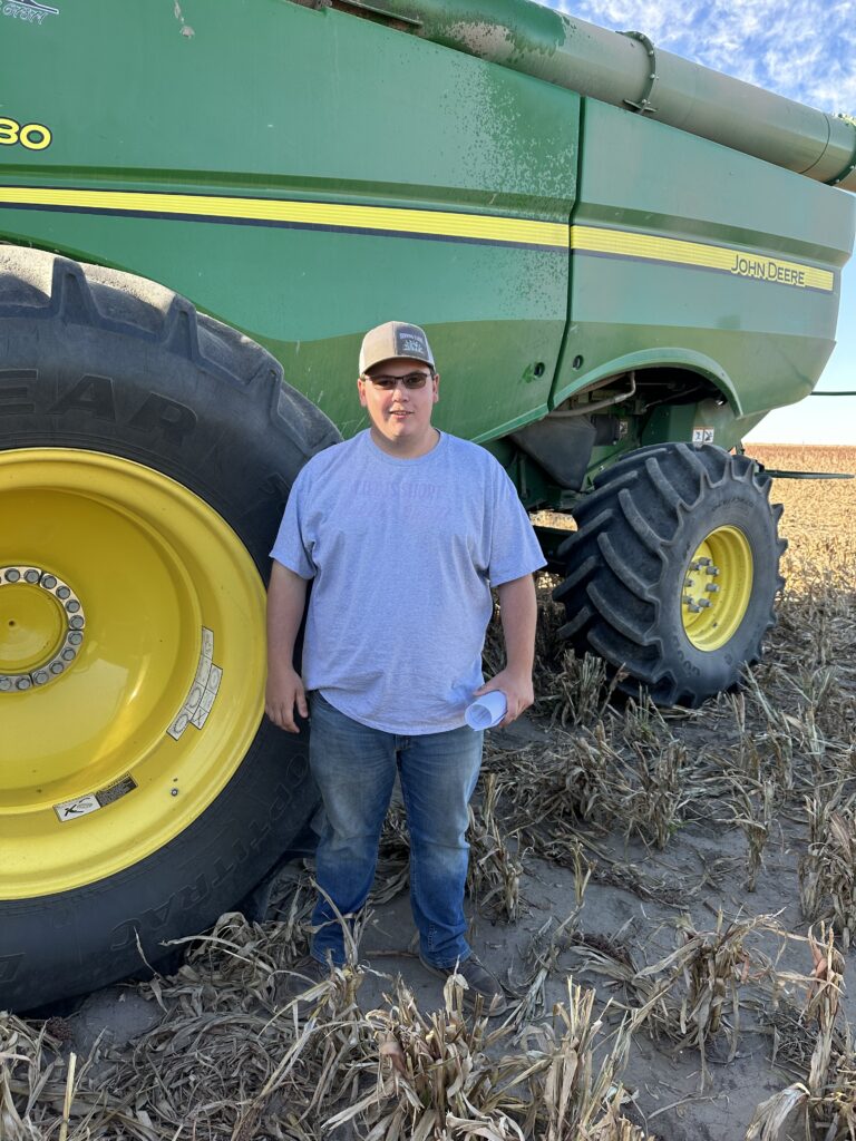 A man standing in front of a large green tractor.