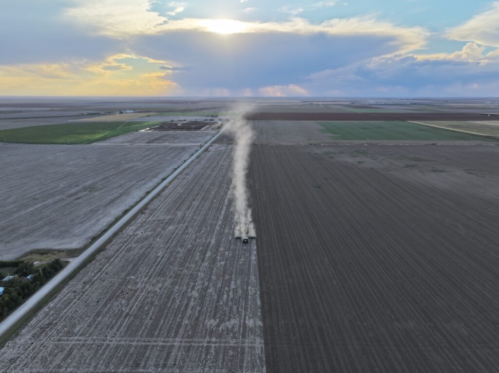 A tractor is driving down the road in an open field.