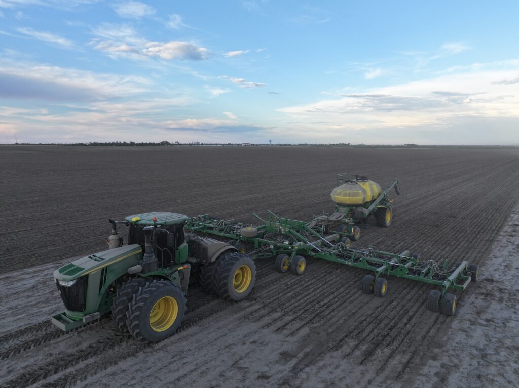 A tractor pulling a trailer in the middle of an empty field.