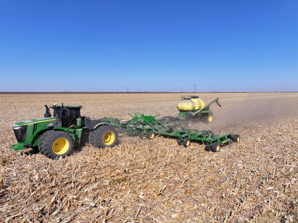 A tractor pulling a trailer on top of dry grass.