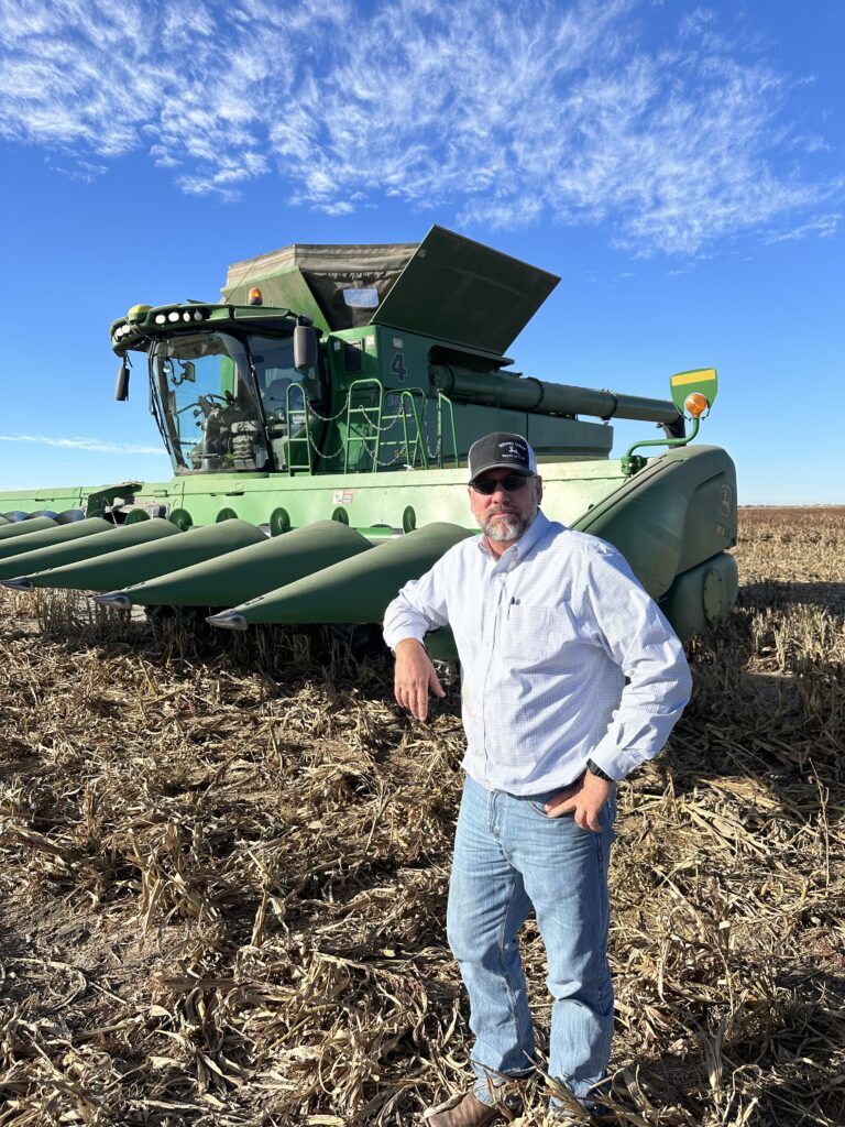 A man standing in front of a green tractor.