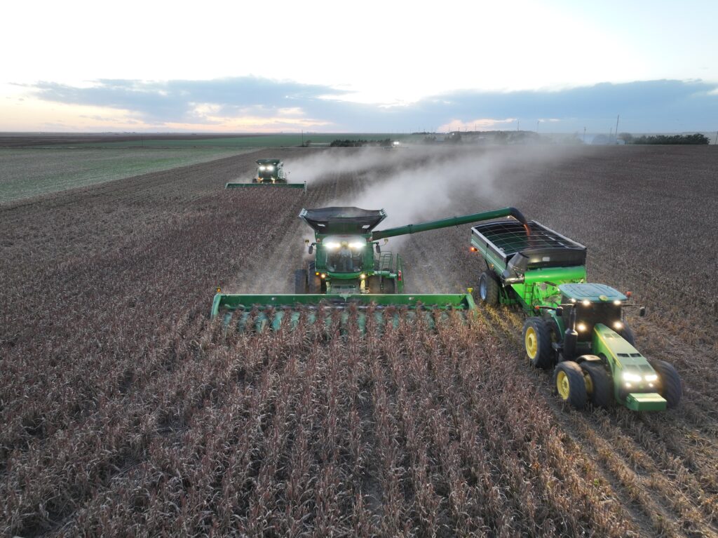 A tractor and two combines in the middle of a field.