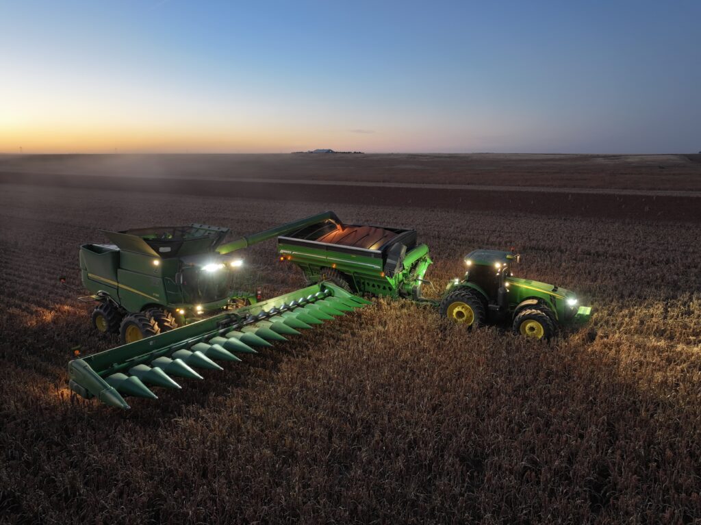 A tractor and two combines in the middle of a field.