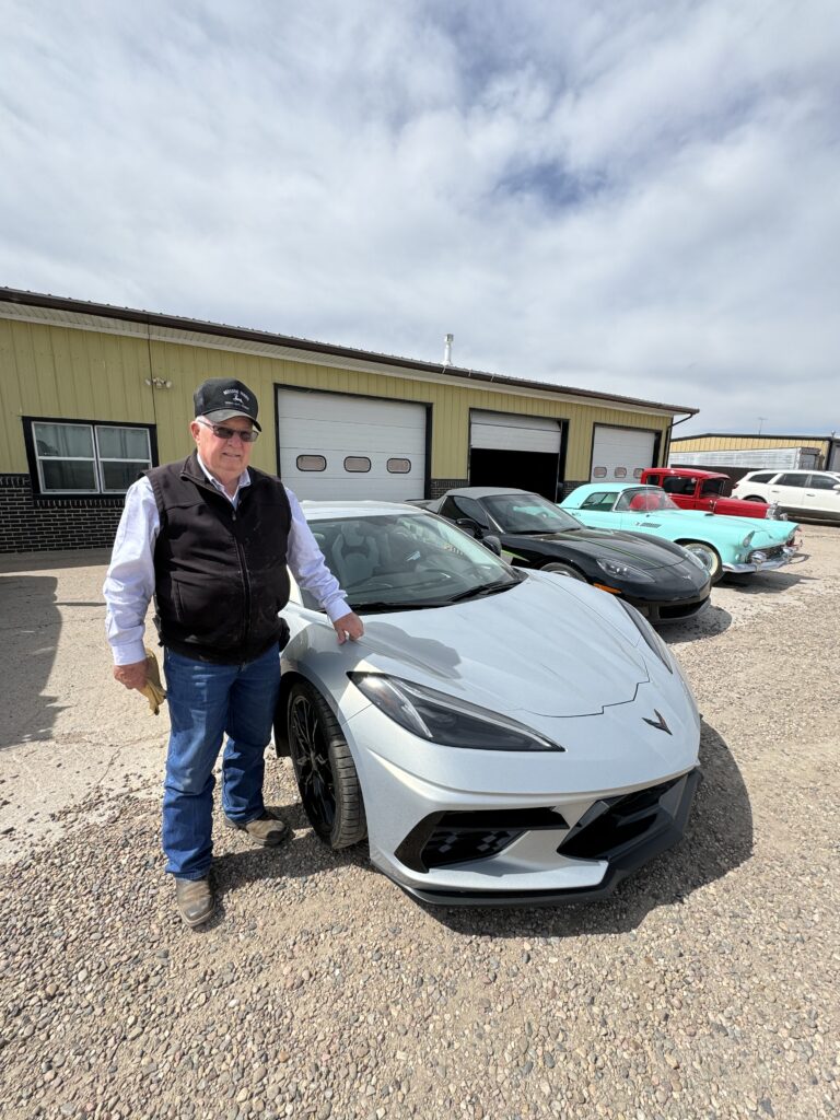 A man standing next to a silver car.